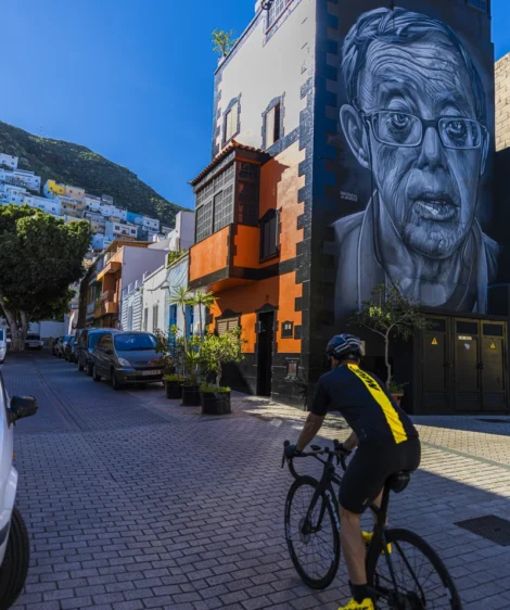 Person Riding a Road Bike on a Street With a Large Painting on the Wall