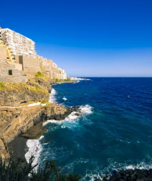 Cliff Side With Building on It and Body of Water Below