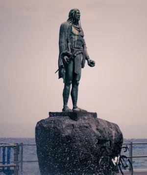 Statue of Man Holding Book on Rock by the Water
