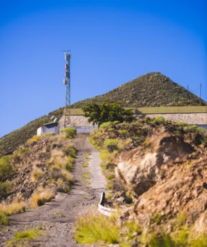 Dirt Road Leading Up to Hill With Building on It