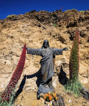 Statue of Person Holding Plant in Front of Rocky Hill