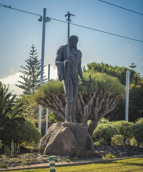 Statue of Person Holding Cross on Rock