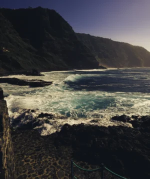 Body of Water With Rocky Shore and Mountain in the Background