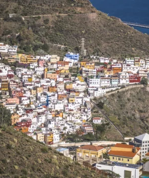 City With Many Buildings and Hill With Body of Water in the Background