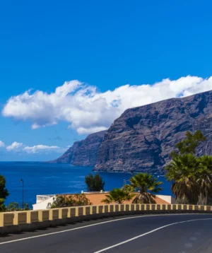 Road Next to Body of Water With Mountains in the Background