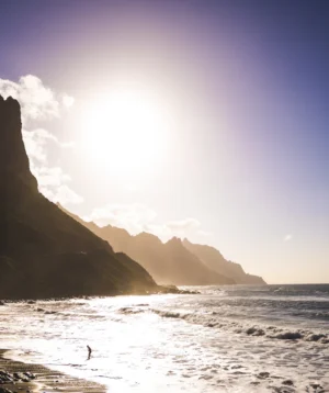 Beach With Large Rock Formation and Body of Water