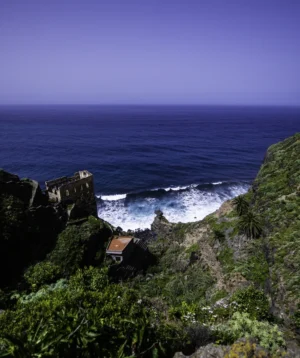 Cliff Side With Building on It and Body of Water in the Background