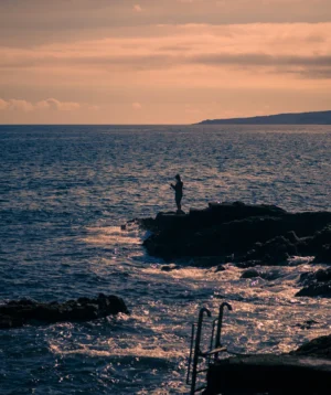 Person Standing on Rock in the Water