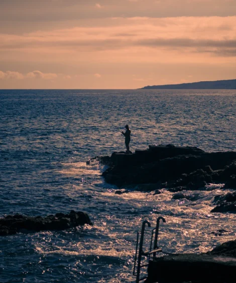 Person Standing on Rock in the Water