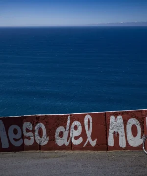 Bicycle Parked on Wall Next to Body of Water