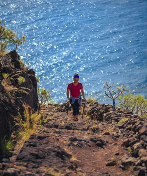 Man Standing on Rocky Hillside by Body of Water